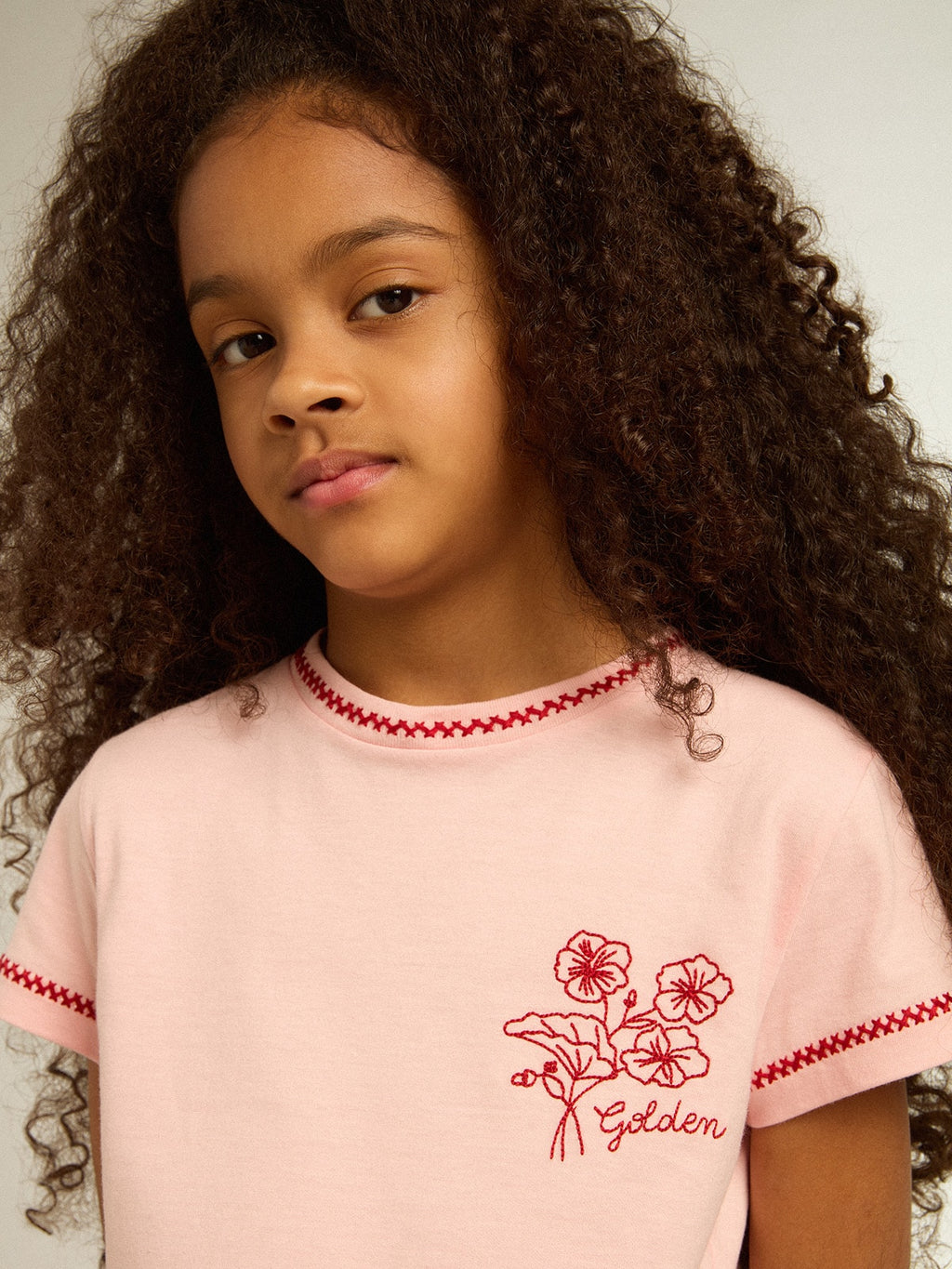 Pink T-shirt with red trim and embroidered flower on the heart