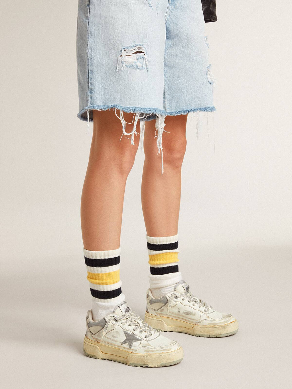 Worn-white socks with distressed details and black and yellow stripes