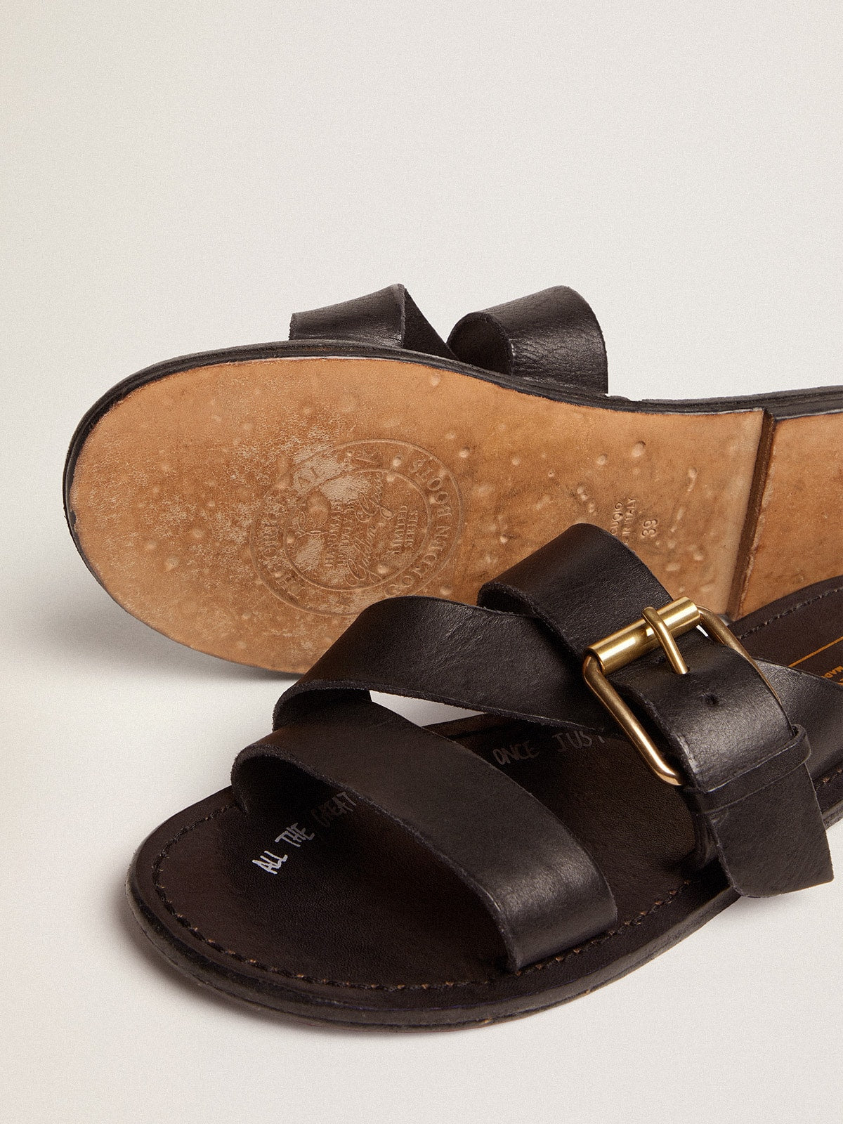 Margaret flat sandals in black resin-coated leather