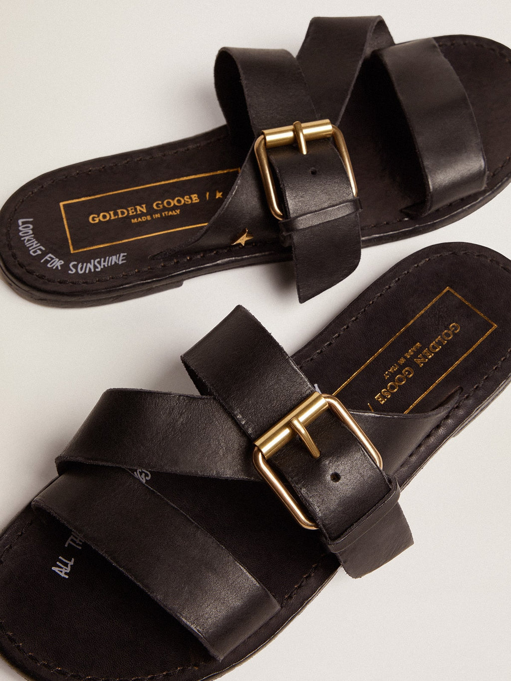 Margaret flat sandals in black resin-coated leather